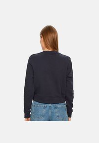 Marineblauwe sweatshirt met een geribbelde ronde hals en manchetten, met een cropped ontwerp. De stof lijkt zacht met een gladde textuur.