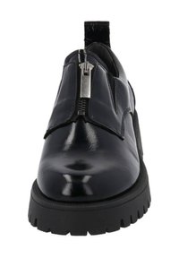 Chaussure en cuir noir brillant avec semelle épaisse noire, fermeture éclair à l'avant et languette à l'arrière.