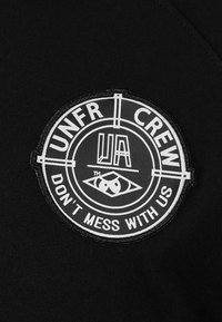 Parche de tela negra con un diseño circular que presenta el texto "UNFR CREW" y "DON'T MESS WITH US", acentuado por un gráfico de un ojo en el centro.