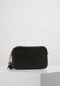 Černá kožená crossbody taška s texturovaným povrchem, zlatými detaily a ozdobným třásní na zipu. Obdélníkový tvar.