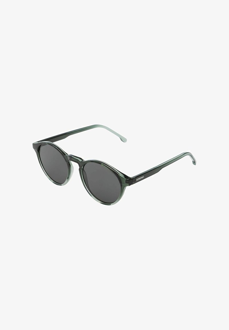Runda solglasögon med mörka linser, grön genomskinlig båge och transparenta skalmar. Har en minimalistisk design med varumärket på skalmen.