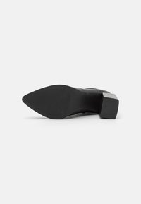 Stivale alla caviglia nero con punta appuntita, tacco a blocco spesso, suola in gomma texturizzata e tomaia in pelle liscia, caratterizzato da dettagli di design minimalisti.