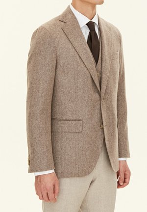 Brown herringbone blazer in textured wool with two front pockets, single button closure, and notched lapels, worn over a white shirt and tie.