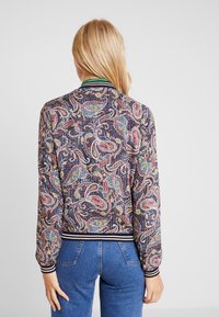 Mønstret bomberjakke i mørk navy, med paisley-motiver i livlige farver. Ribbestrikkede håndled og nederkant med kontraststriber.