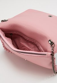 Borsa a mano in pelle rosa con superficie texture, scomparto con zip e tracolla a catena. Include tasche interne per l'organizzazione.