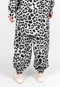 Black and white animal print oversized shirt and joggers, featuring a relaxed fit, elastic cuffs, and paired with light-colored sneakers.
