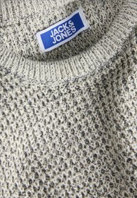 Strickpullover aus strukturiertem Material in Hellgrau mit dunklen Sprenkeln. Mit einem gerippten Kragen und einem blauen Logo-Label mit der Aufschrift "JACK & JONES".