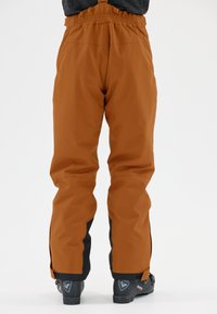 Waterdichte sneeuwbroek in oranje met zwarte accenten, met een elastische tailleband en verstelbare manchetten voor een verbeterde pasvorm en comfort.