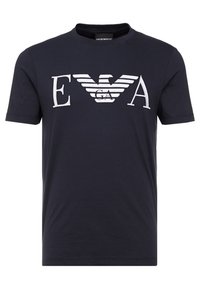 Marinblå bomullströja med korta ärmar, prydd med vita broderade bokstäver "EVA" och en vingad logotypdesign i mitten.