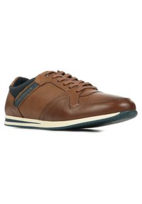 Zapatillas de cuero marrón con textura suave, punta redonda y acentos en azul marino contrastantes. Presentan una suela con rayas blancas y azules marino y cordones.