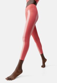 Hooggewaisted leggings in een verloop van roze tinten met contrasterende lichtroze strepen aan de zijkanten, gemaakt van rekbaar materiaal.