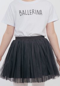 Schwarzer Tüllrock mit gerafftem Design und elastischem Bund, kombiniert mit einem weißen Baumwoll-T-Shirt, das den Text "BALLERINA" in fetten schwarzen Buchstaben trägt.
