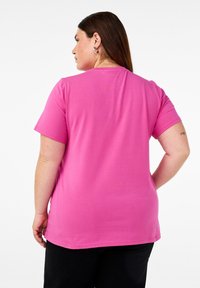Rosa T-Shirt mit kurzen Ärmeln, aus weicher Baumwolle. Hat einen runden Halsausschnitt und eine lockere Passform, mit einer glatten Textur und ohne sichtbare Muster.