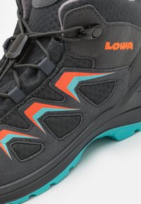 Stivale da trekking nero con dettagli arancioni e teal, upper in tessuto testurizzato e suola robusta. Presenta un sistema di allacciatura sicuro per la personalizzazione della vestibilità.