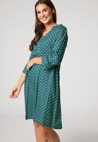 Blauses und grün gemustertes Kleid mit Dreiviertelärmeln, V-Ausschnitt und taillierter Taille, aus glattem, leichtem Material.