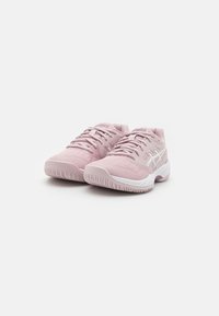 Ténis desportivos rosa claro com malha texturizada e detalhes sintéticos, apresentando realces brancos e uma sola de borracha com padrões de aderência.