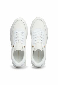 Zapatillas blancas con un upper de cuero liso, diseño de cordones, detalles dorados cerca del talón y suela de goma texturizada.