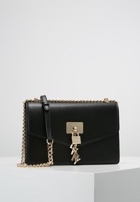 Borsa a mano in pelle nera con hardware dorato, tracolla a catena, pattina frontale e dettaglio con lucchetto. Forma rettangolare, superficie texturizzata e design minimalista.