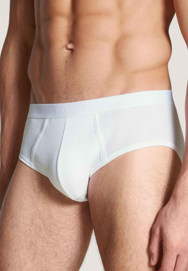 Witte katoenen slip met ribbelstructuur, elastische tailleband met merknaam en een aansluitend ontwerp dat minimale bedekking biedt.