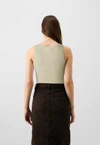 Ριγέ, ανοιχτό πράσινο αμάνικο μπλουζάκι με στρογγυλή λαιμόκοψη, σε συνδυασμό με τζιν φούστα σε σκούρο καφέ χρώμα με ψηλή μέση και τσέπες.