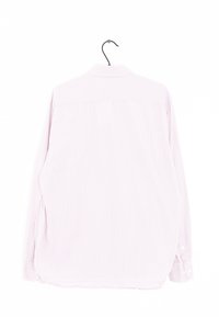 Chemise à manches longues, de couleur rose clair, avec des rayures blanches verticales, texture douce, ourlet arrondi et détails de bouton aux poignets. Suspendue par un crochet.