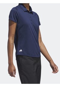 Tmavě modrá polo košile vyrobená z materiálu odvádějícího vlhkost, s klasickým límečkem, třemi knoflíky a logem Adidas na lemu.