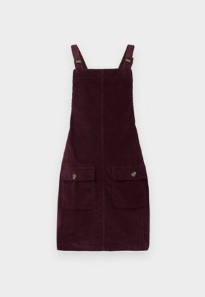 Robe en velours côtelé de couleur bourgogne profond, avec des bretelles ajustables, des poches avant avec quincaillerie en métal et une coupe ajustée. Tissu texturé.
