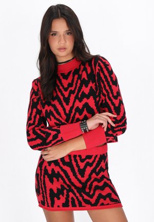 Abito lavorato a maglia rosso e nero con un motivo a zigzag, collo alto e maniche lunghe con polsini e orlo a coste.
