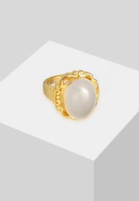 Guld ring med en oval, glat grå sten, omgivet af intrikate filigran detaljer. Båndet er poleret og glat.