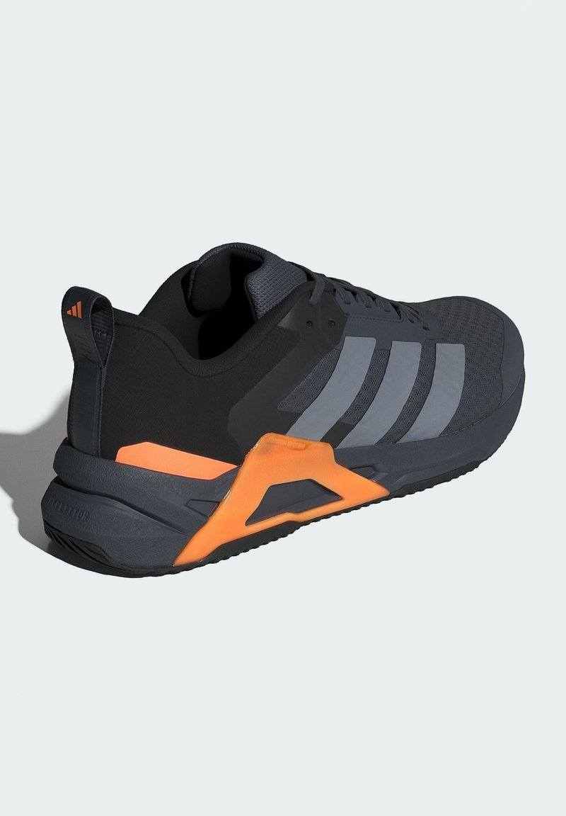 Ciemnoszare i czarne sneakersy Adidas z pomarańczowym wsparciem pięty, sznurowadłami, oddychającą siateczką u góry oraz trzema szarymi paskami po boku.