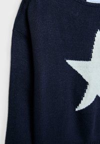 Maritimer Strickpullover in Navy mit einem großen weißen Sternmuster. Der Stoff hat eine glatte Textur und einen gerippten Halsausschnitt sowie Bündchen.