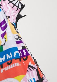 Kolorowy plecak z mieszanką grafik w kolorach czerwonym, żółtym, niebieskim i różowym. Posiada zamek błyskawiczny i teksturowaną tkaninę z błyszczącym wykończeniem.