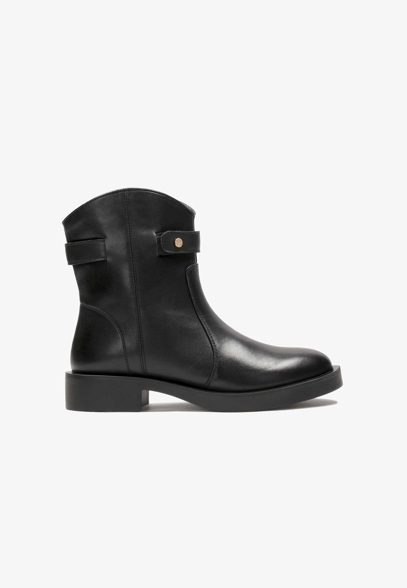 Černá kožená kotníková bota s kulatou špičkou, plochou podrážkou, postranním detailem s přezkou a hladkým povrchem. Obsahuje šev na zadní straně a kruhový akcent.