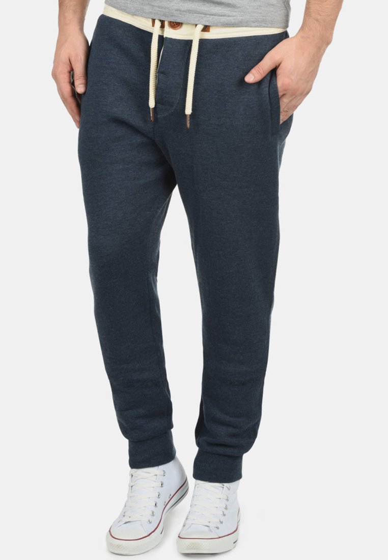 Navy blue sweatpants made of soft fabric, featuring a drawstring waistband and side pockets. Paired with white sneakers.