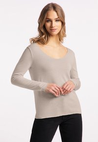 Beige lange mouwen top met een diepe V-hals en aansluitende mouwen. Gemaakt van zachte stof, met een onafgewerkte zoom en een ontspannen pasvorm.