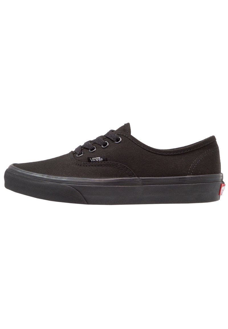 Zapatilla negra de lona con punta redondeada, parte delantera con cordones y suela de goma. Presenta acentos cosidos y un pequeño logo en el costado.