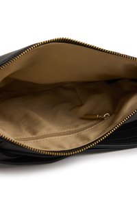 Zwarte leren tas open om de beige stoffen binnenkant te tonen met een klein ritsvakje en een gouden ritssluiting.