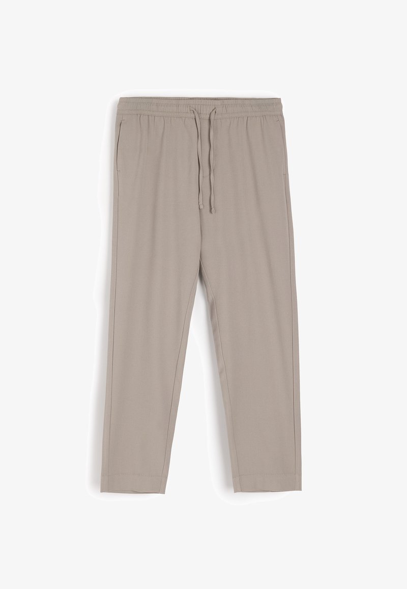 Beżowe spodnie dresowe wykonane z miękkiego materiału, z elastycznym pasem na sznurki, bocznymi kieszeniami i zwężanym krojem nogawki.