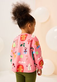 Roza pulover z prazničnimi vzorci, vključno z medenjaki, severnimi jeleni, snežaki, darili in šipkom, z dolgimi rokavi in okroglim izrezom.