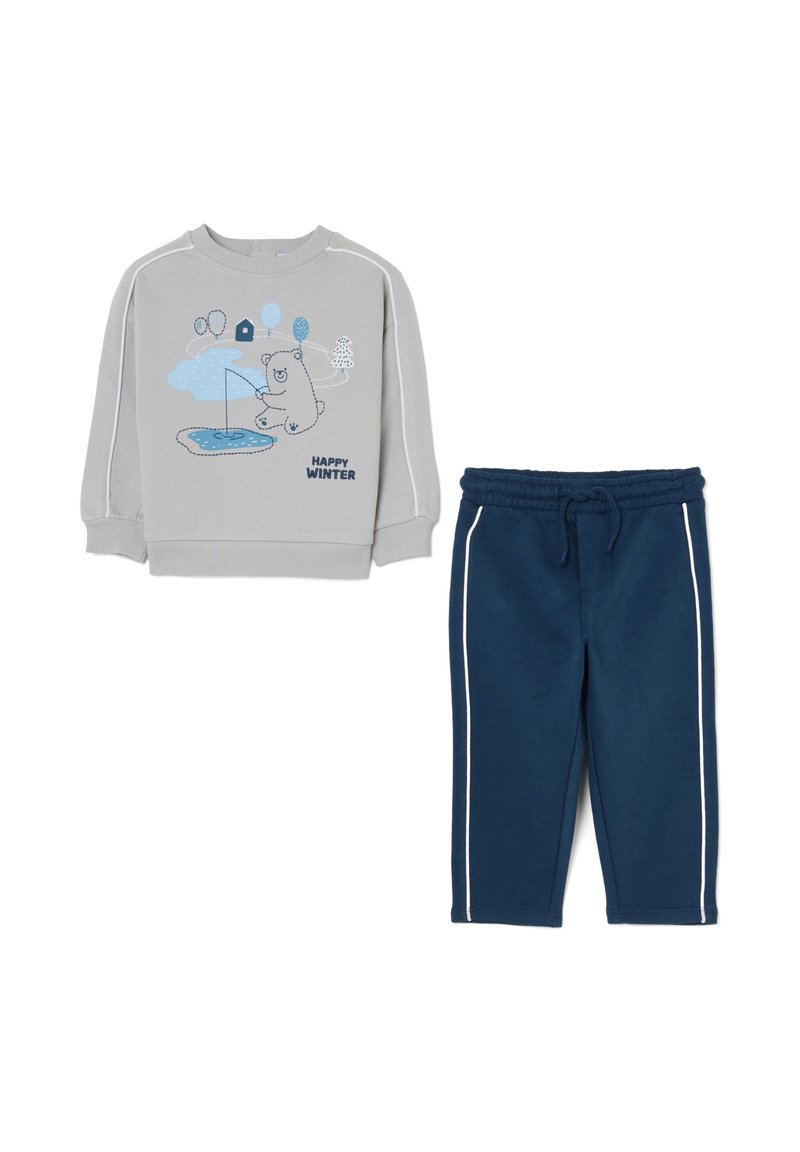 Felpa grigia con grafica di un orso blu e testo "HAPPY WINTER"; abbinata a pantaloni della tuta blu navy con strisce bianche sui lati e vita elastica.
