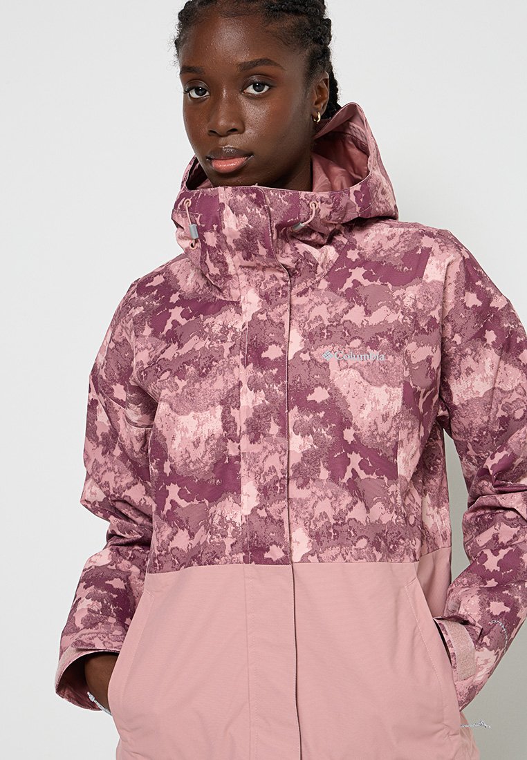 Lila und rosa gemusterte Jacke mit hohem Kragen, Reißverschluss vorne und großen Taschen. Glatte Textur mit einem Farbblockdesign.