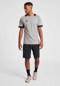 Grå sports T-shirt med sorte detaljer, korte ærmer og tekstureret design; parret med sorte shorts og lyse sneakers.