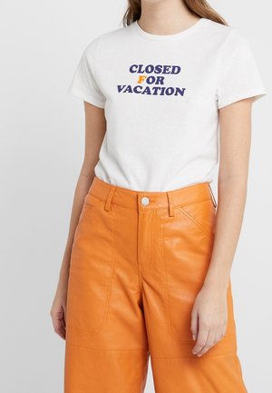Hvid bomulds t-shirt med blå og orange tekst, der står "LUKKET FOR FERIE." Sammen med orange faux læderbukser.