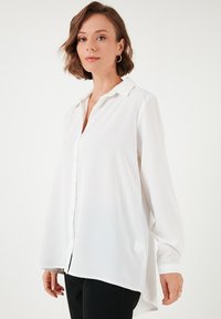Weiße Bluse mit Kragen aus glattem Stoff, mit Knopfverschluss, langen Ärmeln und leicht abgerundetem Saum.
