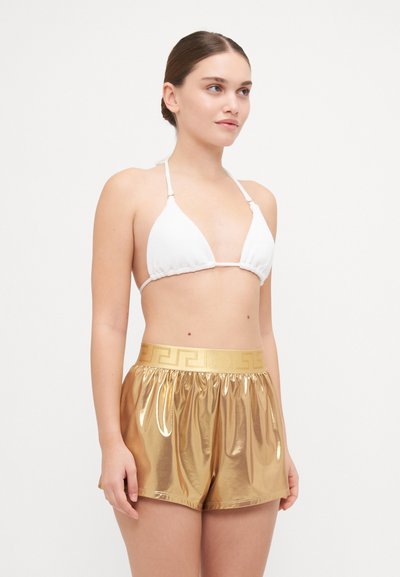 Haut de bikini triangle blanc et shorts métalliques dorés avec une taille élastique présentant un design décoratif. Texture lisse, coupe décontractée.