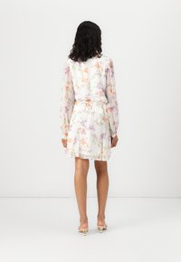 Robe à imprimé floral avec des manches longues, base blanche, taille cintrée et jupe fluide. Présente des fleurs colorées et un tissu doux et texturé.