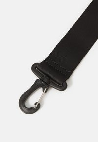 Sort nylonrem med en glat overflade, der har en metalclips og en plastikhook-tilslutning til sikring af genstande.