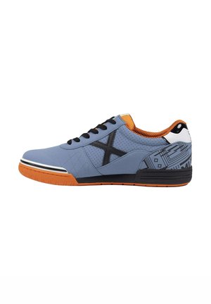 Zapatilla baja con empeine azul claro, cordones negros, logo X lateral negro, forro interior naranja y suela de goma naranja con detalles en negro y blanco.