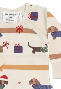 Langærmet heldragt i off-white bomuld, med illustrationer af gravhunde og gaver i rød og blå. Trykknaplukning ved skulderen.