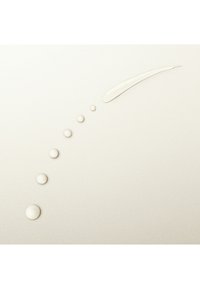 Gouttes de liquide clair et une trace courbée sur une surface lisse de couleur claire présentant des tailles et textures variées.